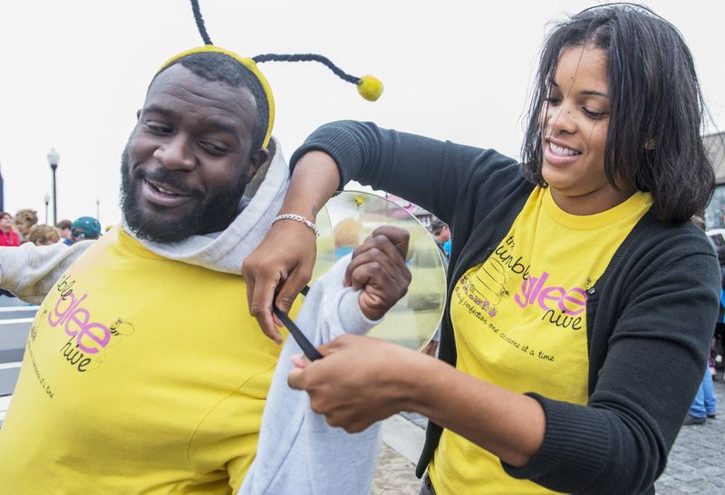 Team Bumble Glee Hive gets dressed for the walk. Jordan Thomas gets a hand with his wings from Jessica Dubois. BY DENY HOWETH